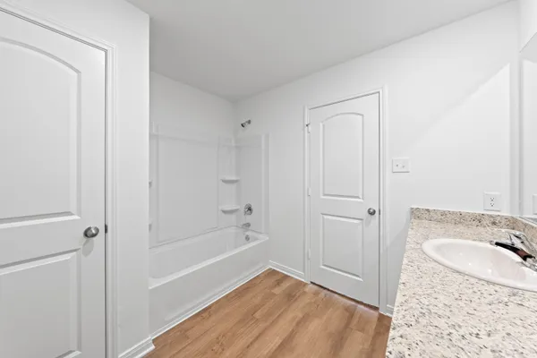 a bathroom with a granite countertop sink a mirror and a bathtub