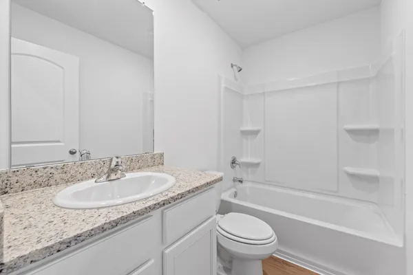 a bathroom with a granite countertop sink a toilet and a bathtub