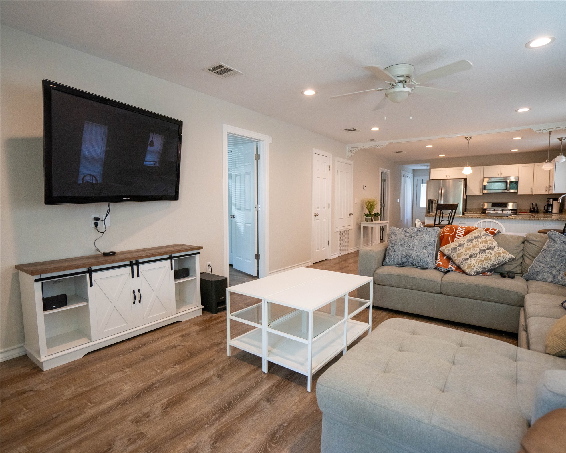 404 Rivers Street Smithville, TX 78957 - Photo 11 of 27 Open-concept living space featuring wood-finish flooring, a ceiling fan with integrated lighting, recessed lighting, and a barn door style media console