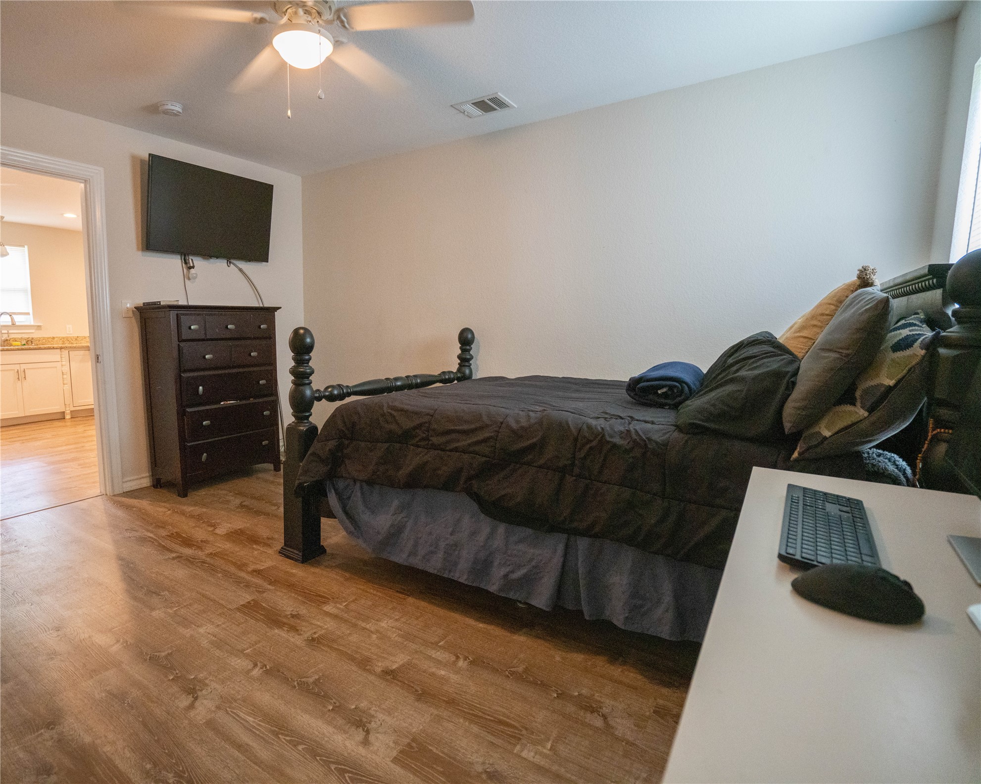 404 Rivers Street Smithville, TX 78957 - Photo 18 of 27 Room featuring wood-finish flooring, a ceiling fan with integrated lighting, and a wall-mounted television bracket