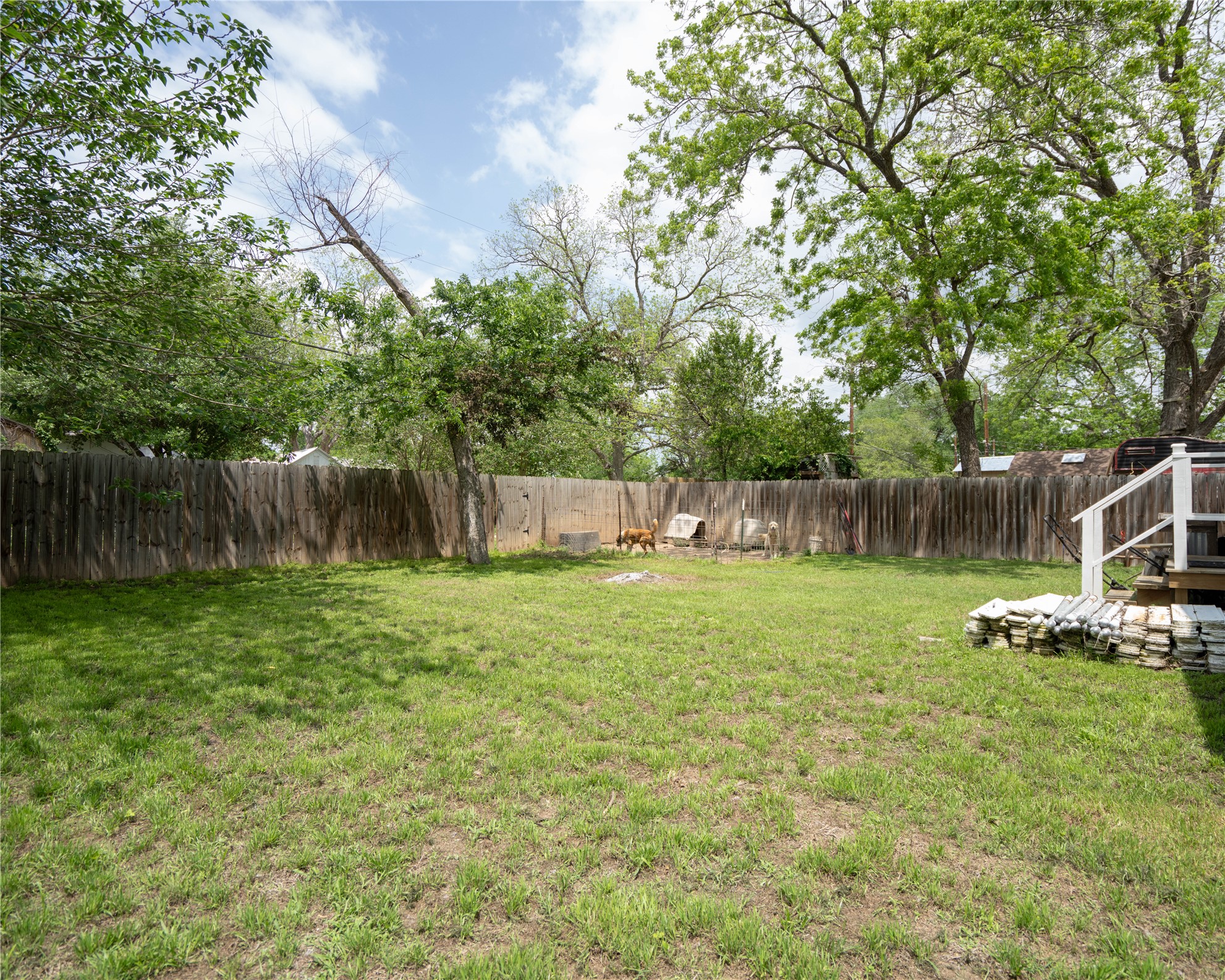 404 Rivers Street Smithville, TX 78957 - Photo 19 of 27 Expansive backyard featuring a wood privacy fence, mature trees, and a wooden deck with white railings