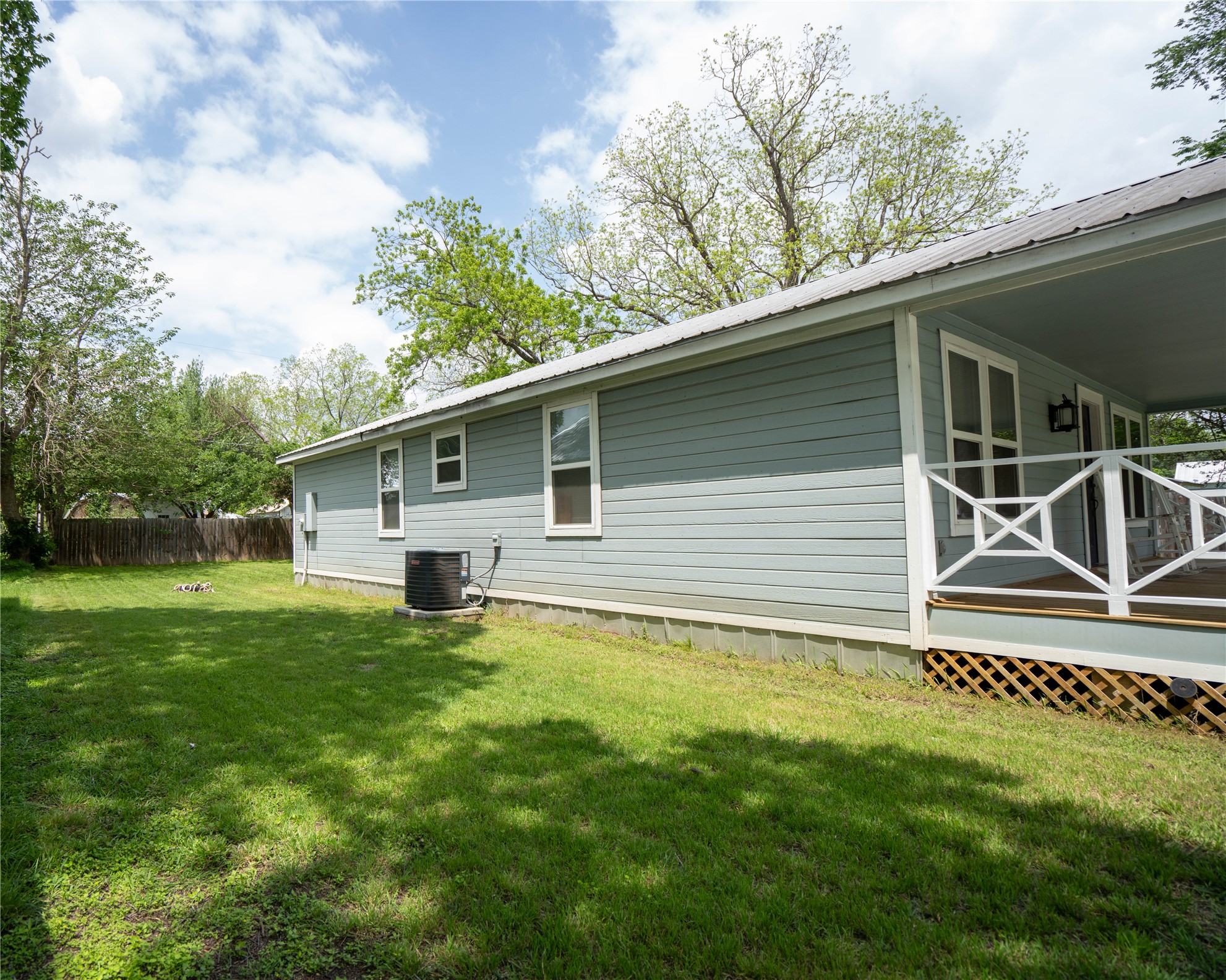 404 Rivers Street Smithville, TX 78957 - Photo 20 of 27 Spacious backyard featuring a manicured lawn, established trees, and a wooden privacy fence