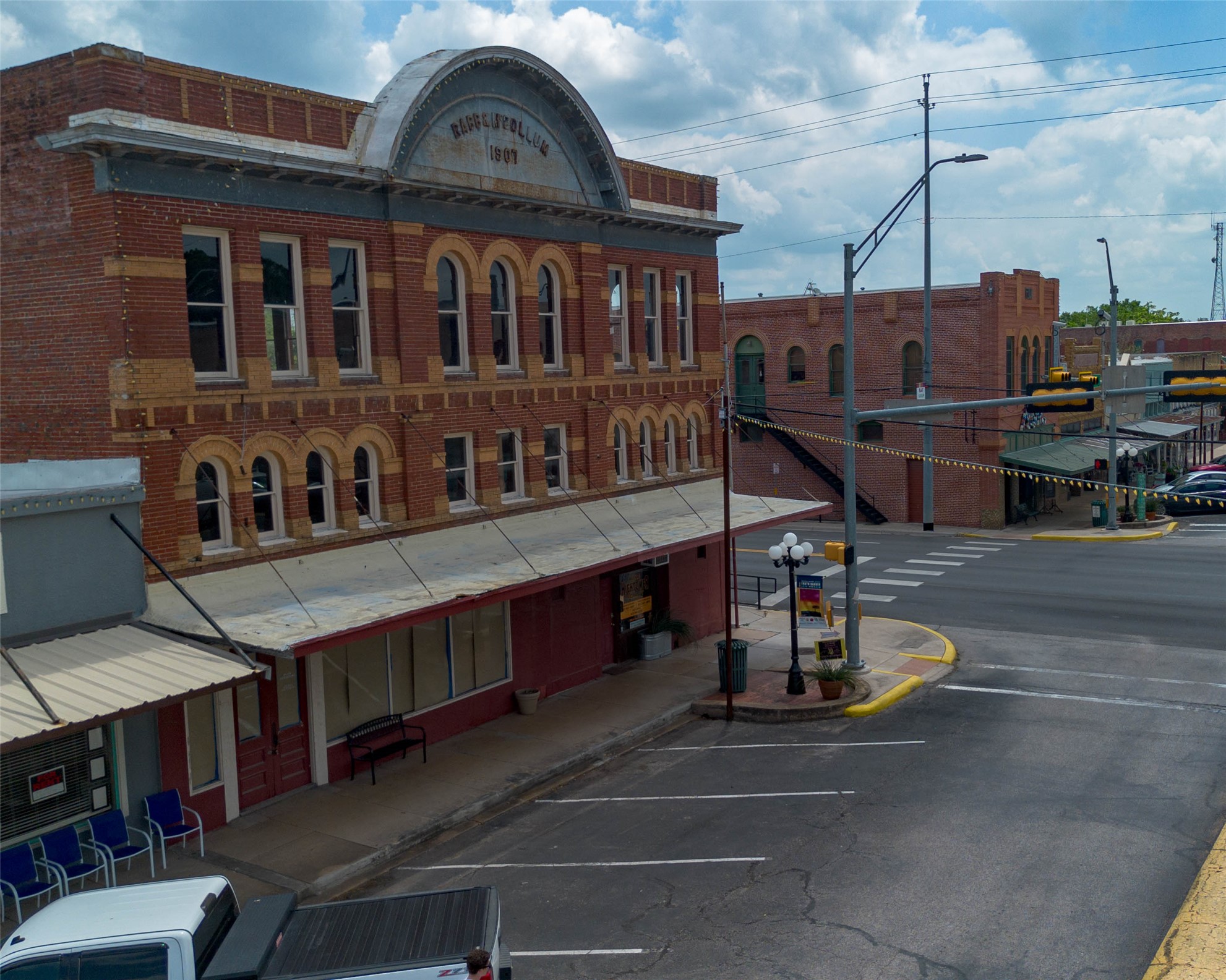 404 Rivers Street Smithville, TX 78957 - Photo 25 of 27 Historic brick building featuring arched windows with stone sills, a decorative cornice, and a prominent arched pediment with inscribed lettering