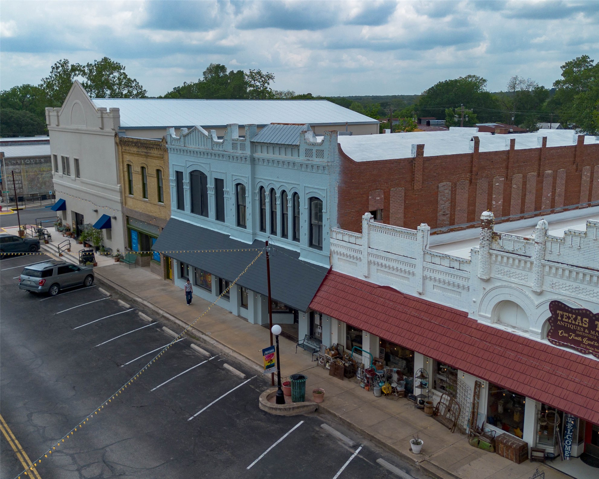 404 Rivers Street Smithville, TX 78957 - Photo 27 of 27 Historic commercial buildings featuring a light blue facade with arched windows, a beige building with blue awnings, a white building with an ornate parapet, and a red brick building