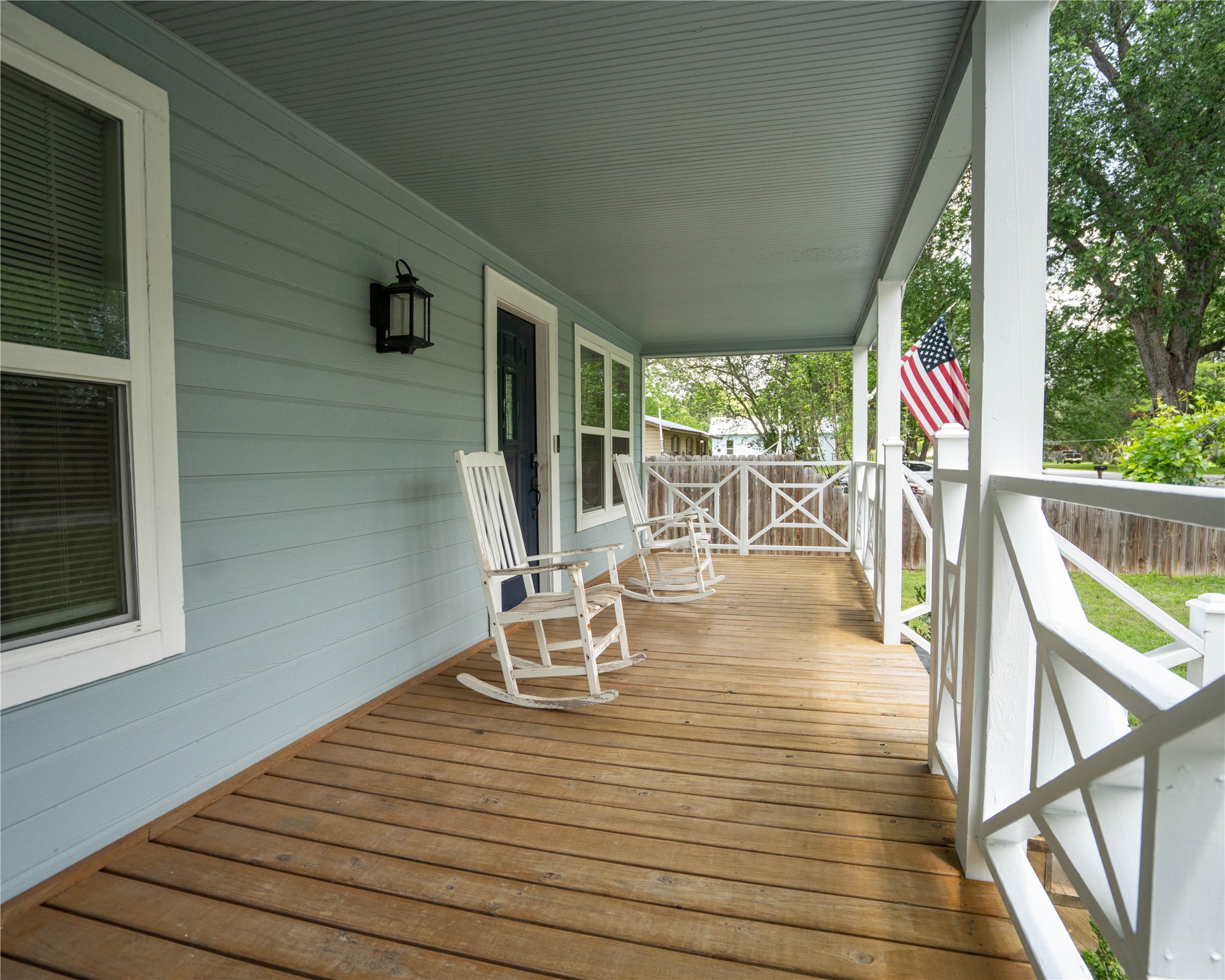 404 Rivers Street Smithville, TX 78957 - Photo 3 of 27 Covered front porch featuring wood-finish flooring, light blue siding, white trim, and decorative railing