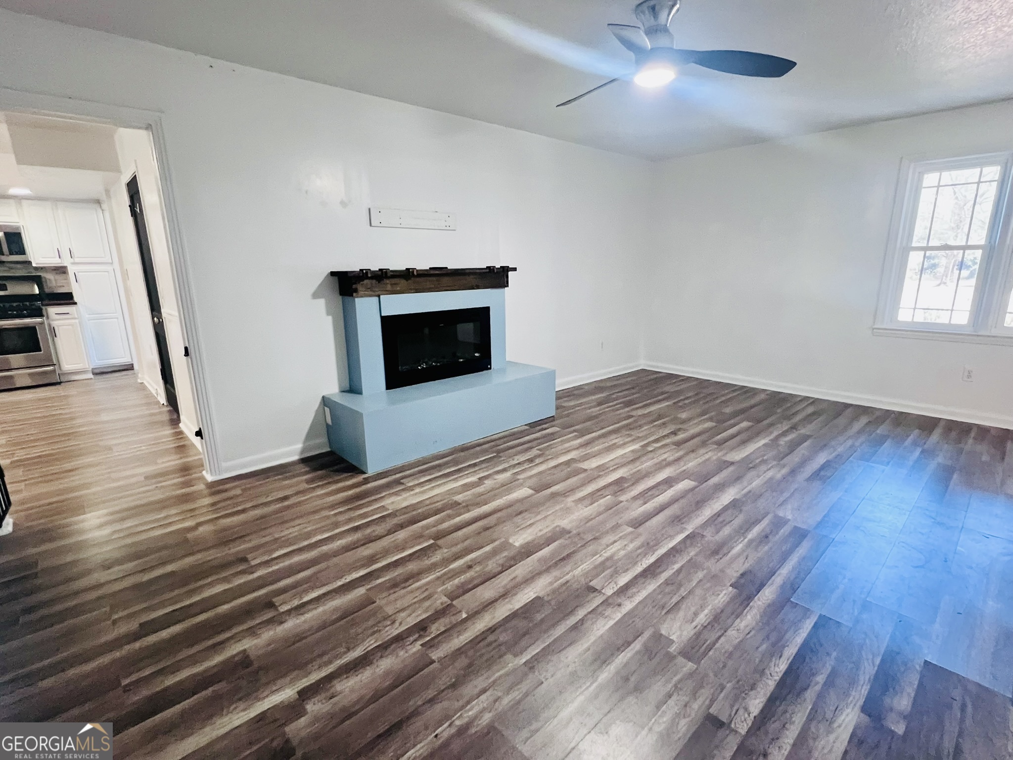 594 South 3rd Street Jesup, GA 31545 - Photo 11 of 32 an empty room with wooden floor fireplace and stairs