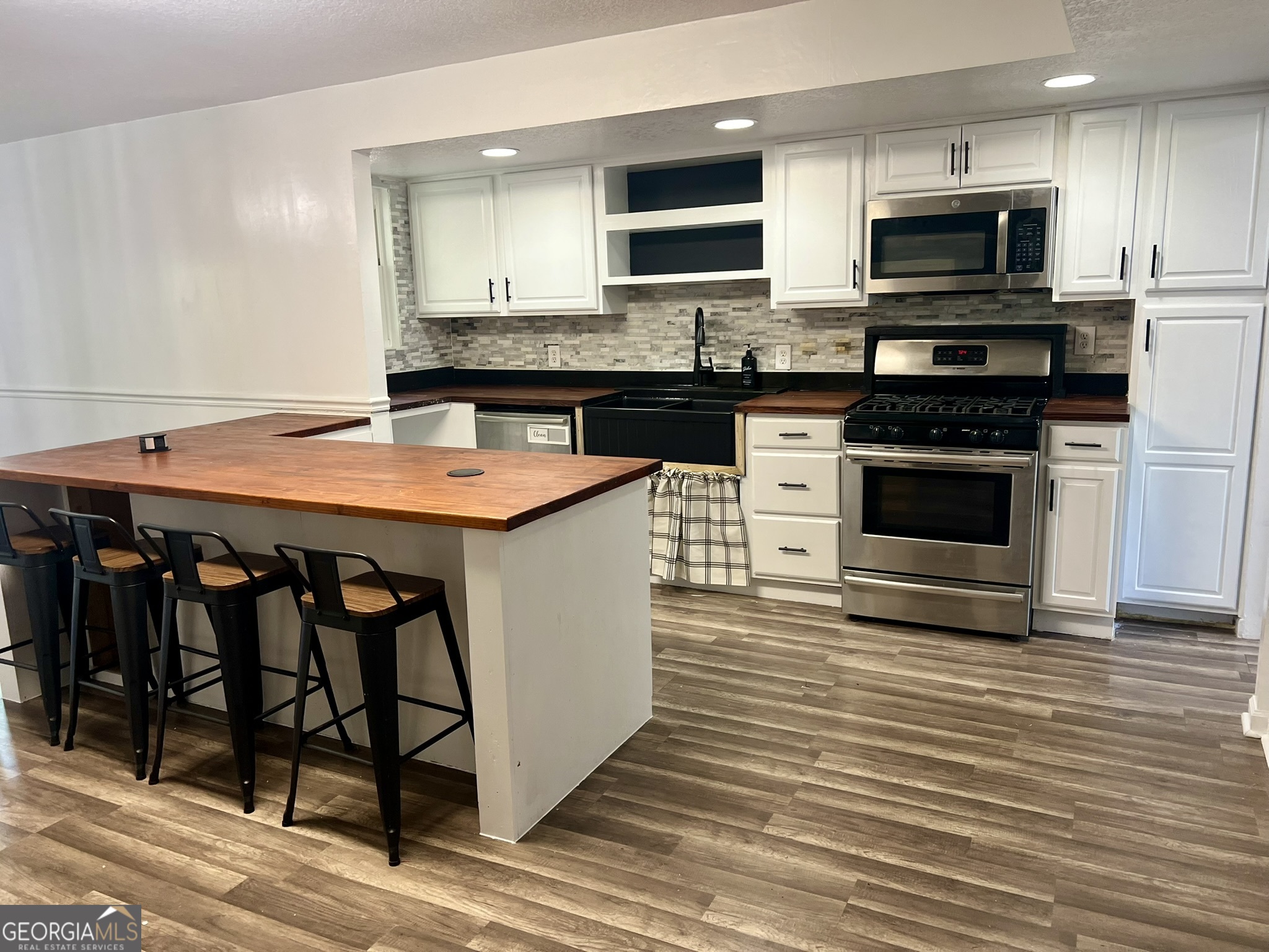 594 South 3rd Street Jesup, GA 31545 - Photo 13 of 32 a kitchen with stainless steel appliances kitchen island granite countertop a stove a sink and a microwave