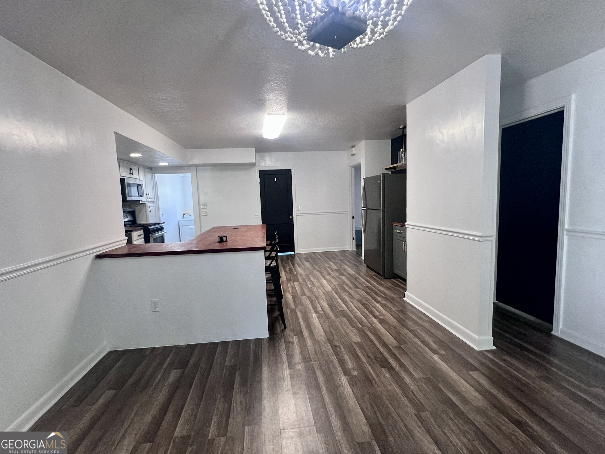 594 South 3rd Street Jesup, GA 31545 - Photo 17 of 32 a view of a refrigerator in kitchen and an empty room with wooden floor