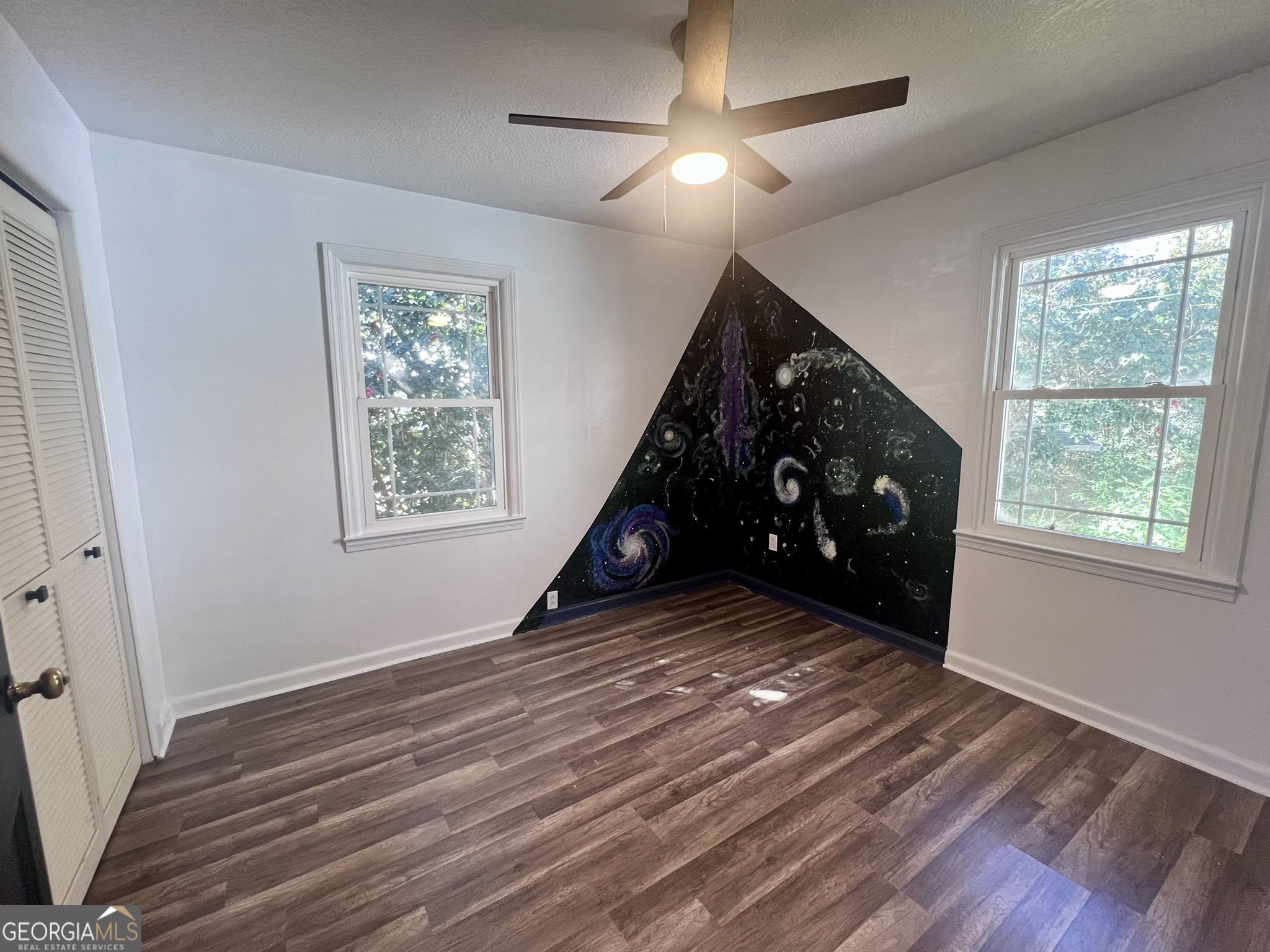 594 South 3rd Street Jesup, GA 31545 - Photo 7 of 32 a view of an empty room with wooden floor ceiling fan and windows