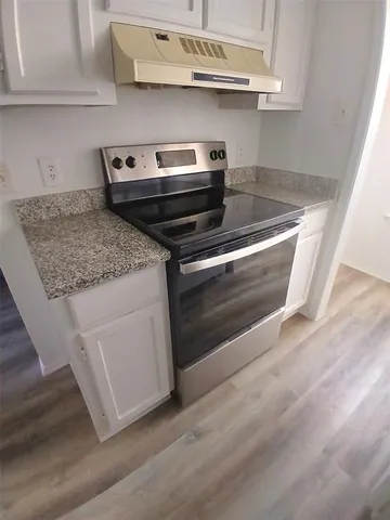 a view of a hallway with wooden floor and a bathroom