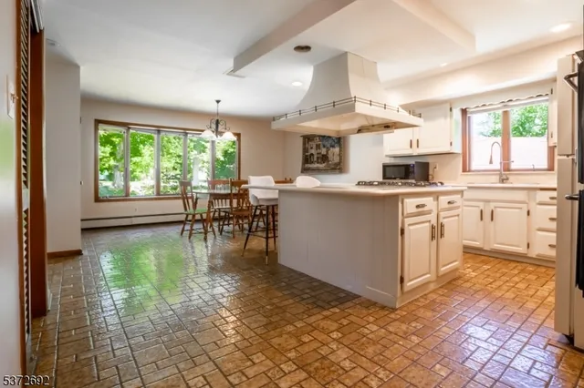 a kitchen with kitchen island granite countertop a stove a sink a counter top space and living room view