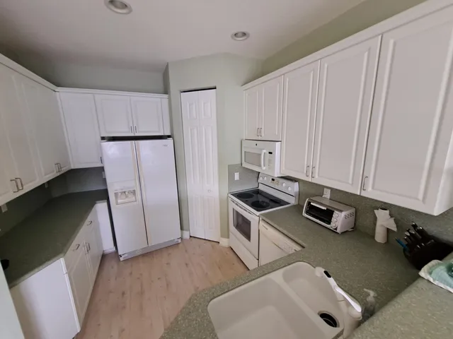 a kitchen with stainless steel appliances a refrigerator a sink a stove and white cabinets