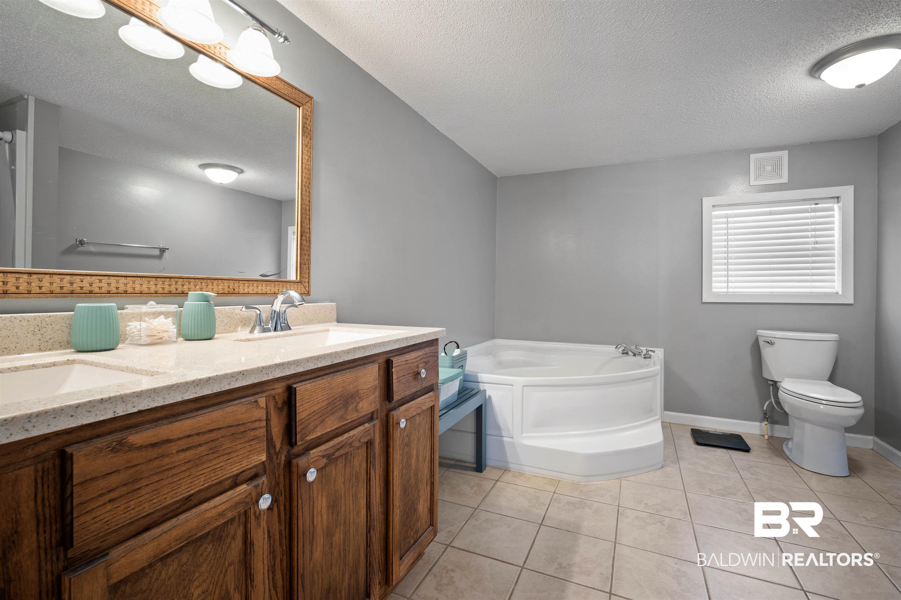 9011 Wilmer Georgetown Road Wilmer, AL 36587 - Photo 15 of 34 Bathroom with a garden tub, a sink, toilet, and tile patterned flooring