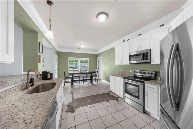 a kitchen with stainless steel appliances granite countertop a sink a stove top oven a dining table and chairs