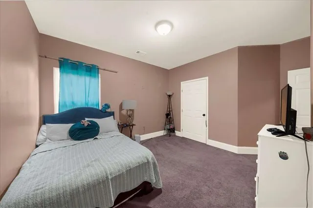 a bedroom with a bed and a flat tv screen on dresser