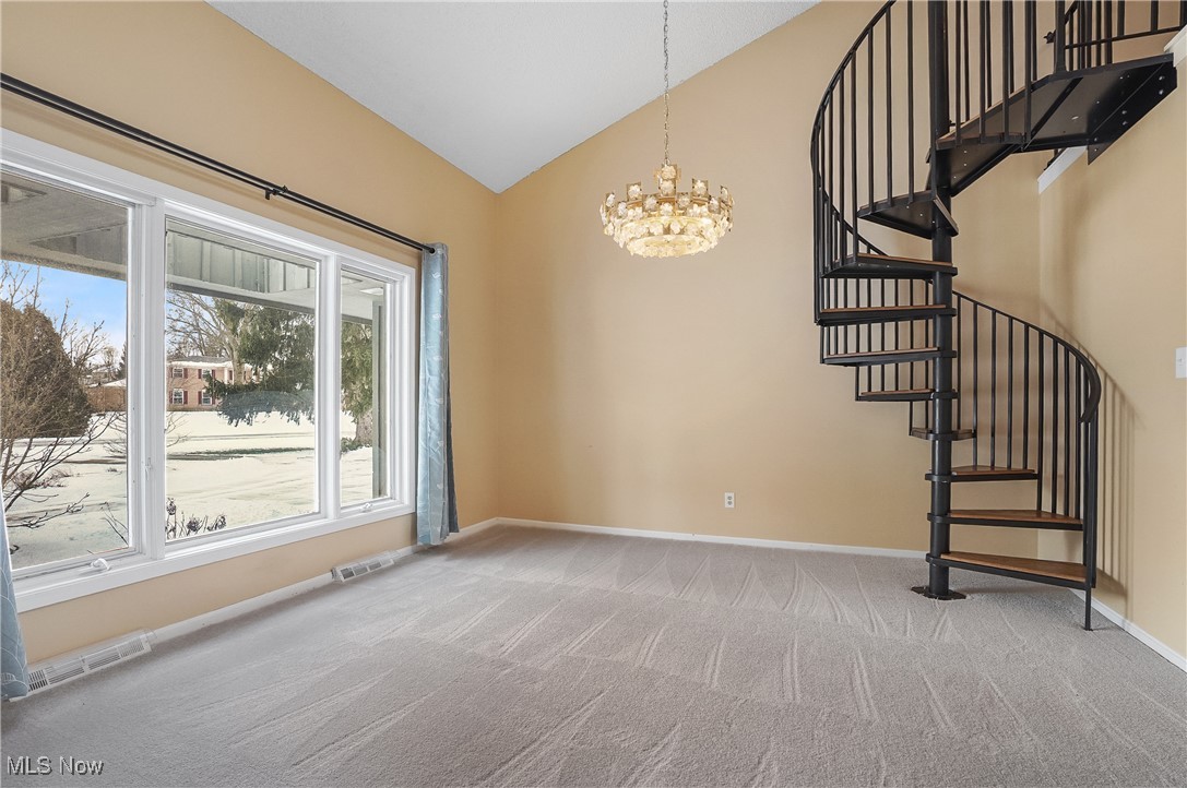 1094 San Raphael Drive Akron, OH 44333 - Photo 24 of 50 Empty room featuring stairway, light carpet, a chandelier, and high vaulted ceiling