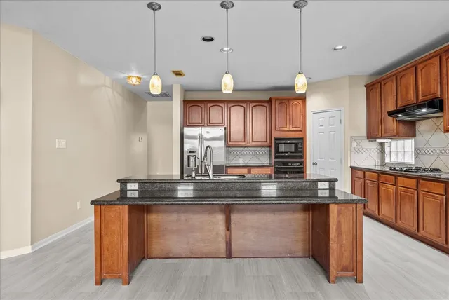 a kitchen with granite countertop wooden cabinets