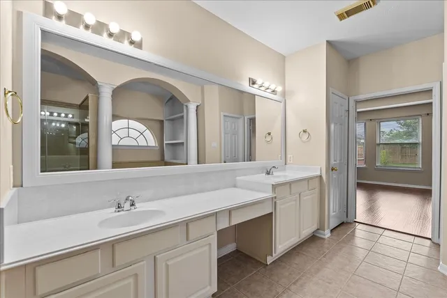 an empty room with a chandelier fan and windows