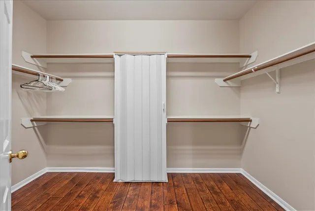 an empty room with wooden floor and a ceiling fan
