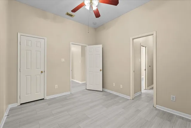 a view of an empty room and chandelier fan