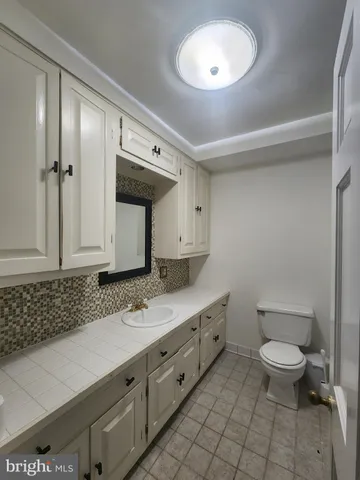 a spacious bathroom with a granite countertop sink a toilet and mirror