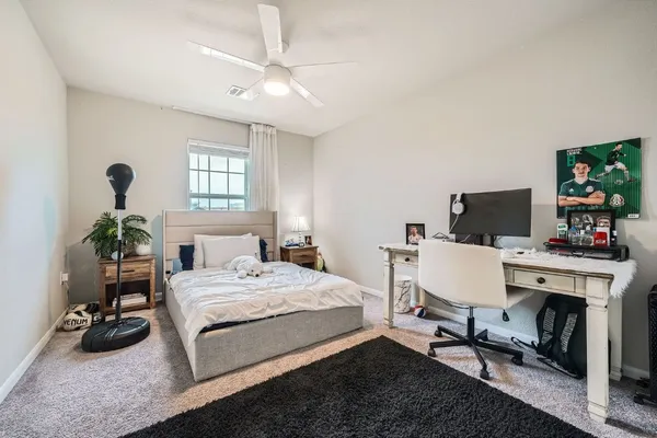 a bedroom with a bed a computer on desk and a dresser next to a window