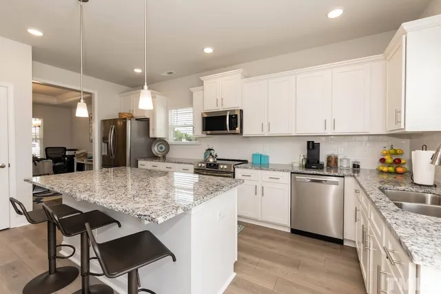 a kitchen with stainless steel appliances granite countertop a stove top oven a sink refrigerator and cabinets