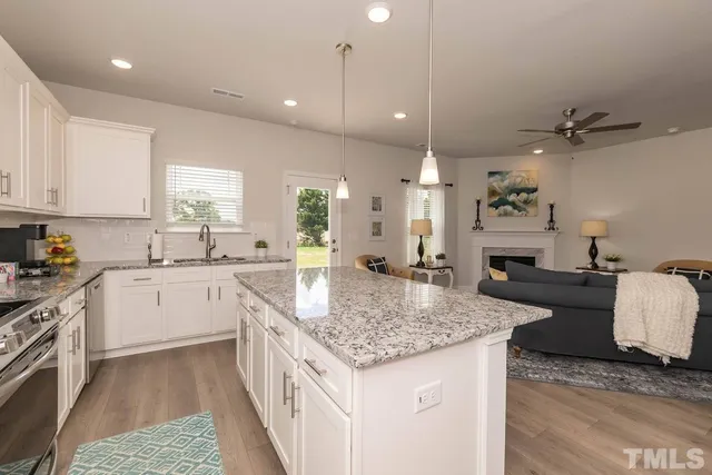 a kitchen with granite countertop kitchen island stainless steel appliances a sink stove and cabinets