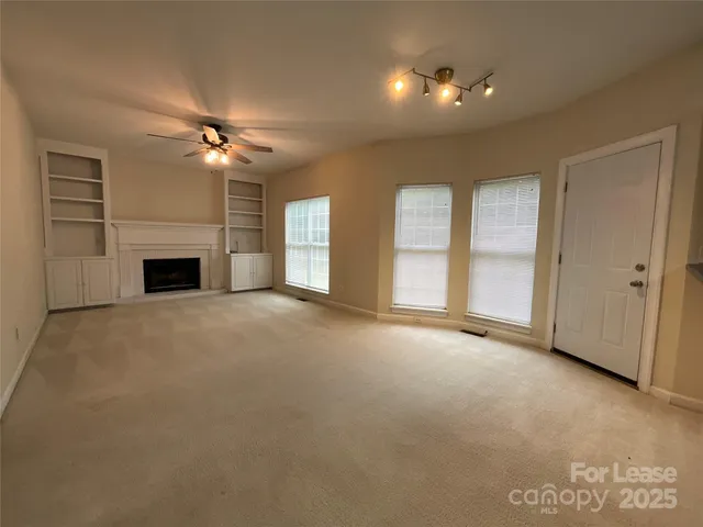 an empty room with windows and fireplace