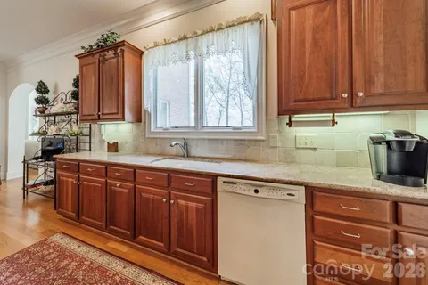 a kitchen with stainless steel appliances granite countertop wooden cabinets a sink and dishwasher with wooden floor