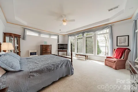 a spacious bedroom with a bed and glass walk in closet