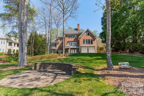 a view of a brick house with a big yard and large trees