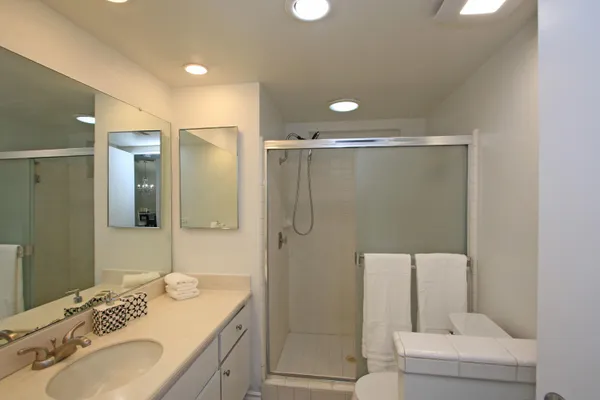 a bathroom with a granite countertop sink a mirror a shower and a toilet