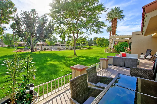 a view of a patio with couches dining table and chairs with wooden fence and trees