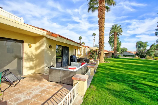 a view of a patio with couches table and chairs and potted plants