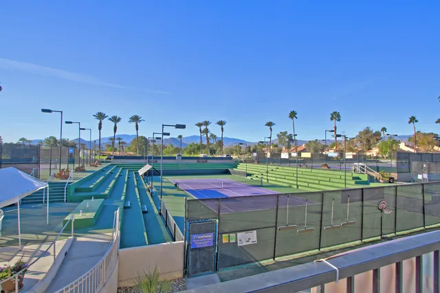 a view of a tennis ground with large trees