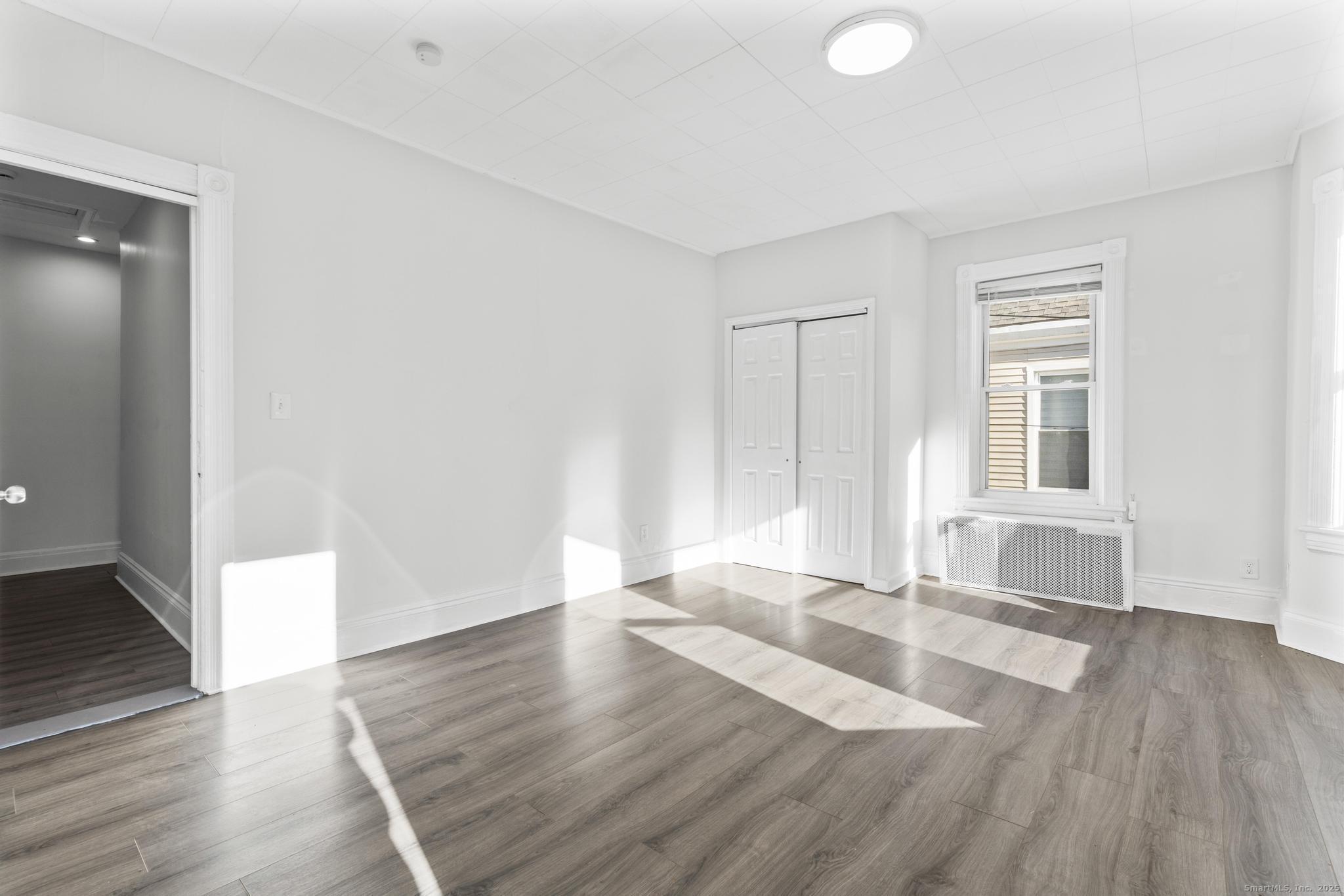 394 Gregory Street, Unit 4 Bridgeport, CT 06604 - Photo 21 of 23 an empty room with wooden floor and windows