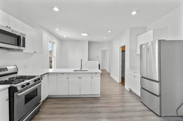 a large kitchen with stainless steel appliances granite countertop a stove a sink and a refrigerator