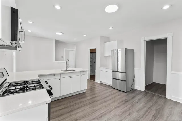 a kitchen with stainless steel appliances a sink a stove a refrigerator and cabinets