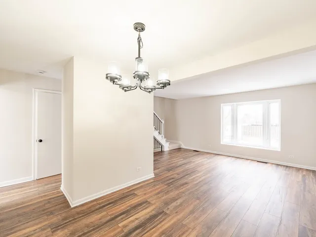 a view of a room with wooden floor chandelier and a window