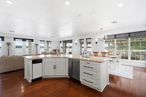 a kitchen with stainless steel appliances kitchen island granite countertop a stove and white cabinets with wooden floor