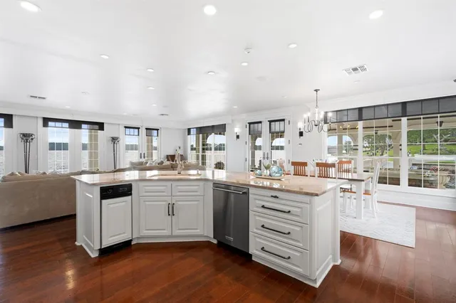 a kitchen with stainless steel appliances kitchen island granite countertop a stove and white cabinets with wooden floor