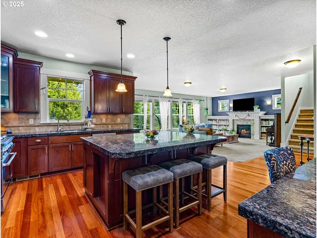 a kitchen with stainless steel appliances granite countertop a table chairs refrigerator and microwave