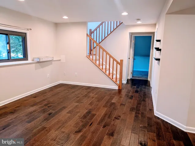 a view of an empty room with wooden floor and closet