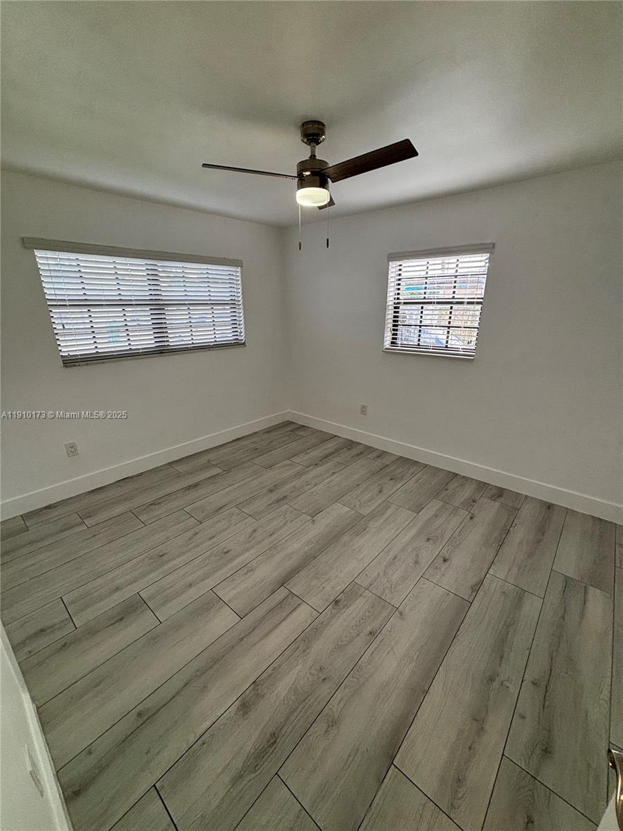 17110 Northwest 11th Avenue Miami Gardens, FL 33169 - Photo 17 of 38 an empty room with wooden floor ceiling fan and windows