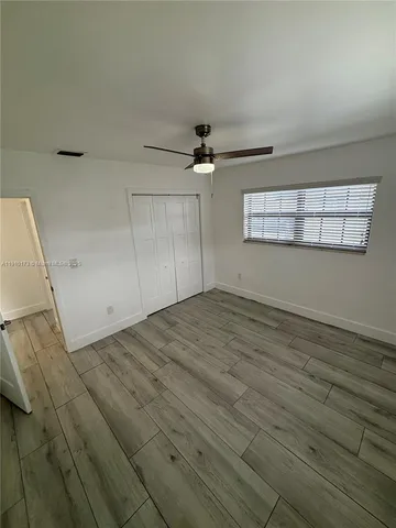 an empty room with wooden floor ceiling fan and windows