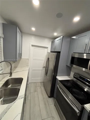 a kitchen with a sink a refrigerator and a stove top oven with wooden floor