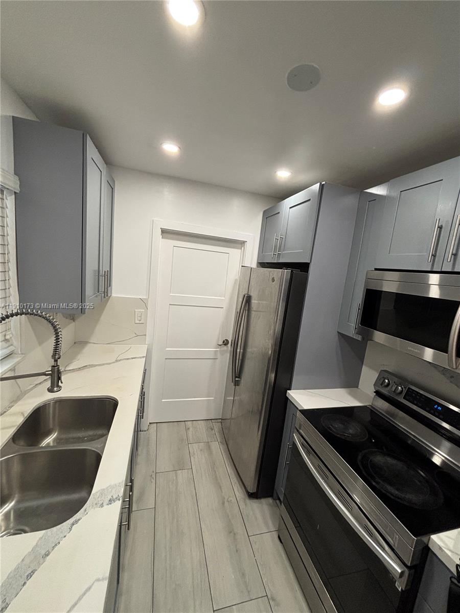 17110 Northwest 11th Avenue Miami Gardens, FL 33169 - Photo 6 of 38 a kitchen with a sink a refrigerator and a stove top oven with wooden floor