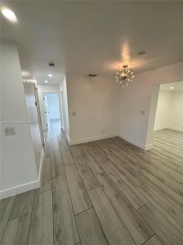 an empty room with wooden floor and chandelier