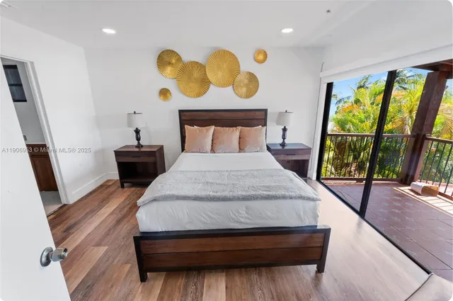 a bedroom with a bed and dresser with wooden floor